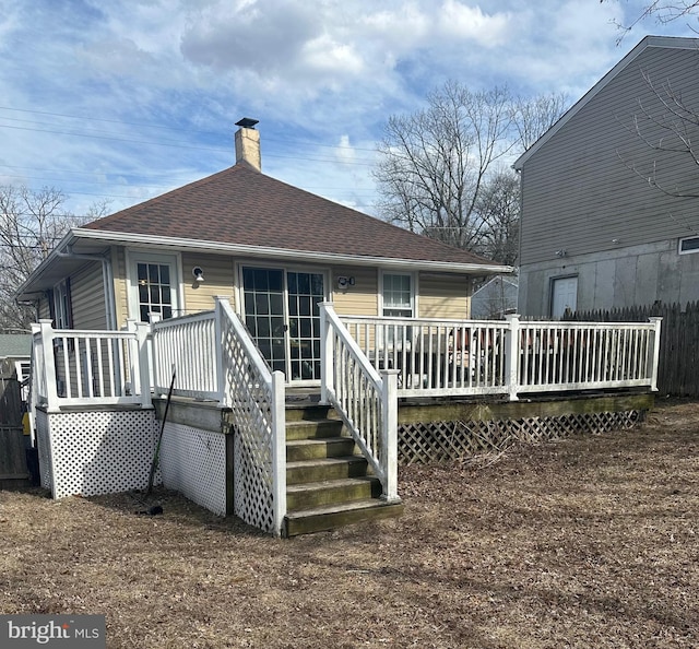 back of house featuring roof with shingles, a chimney, and a wooden deck