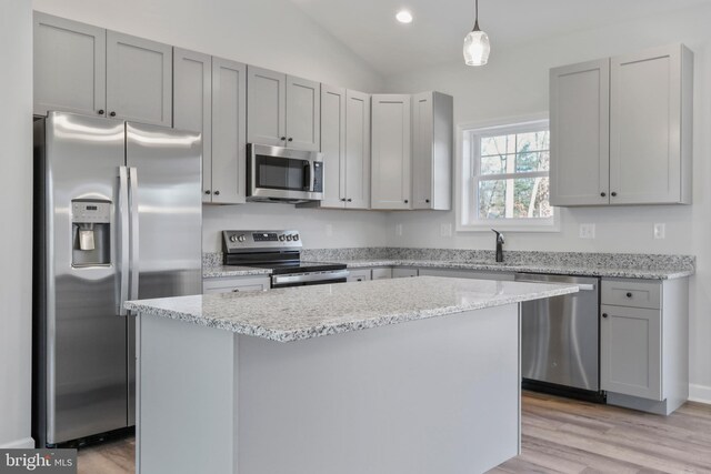 kitchen featuring stainless steel appliances, a center island, vaulted ceiling, and light wood finished floors