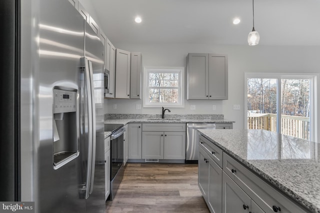 kitchen with stainless steel appliances, recessed lighting, dark wood-type flooring, a sink, and light stone countertops