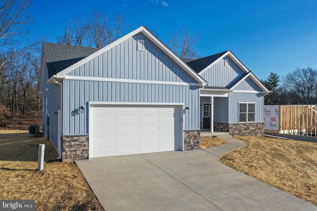 modern farmhouse style home with a garage, stone siding, board and batten siding, and roof with shingles