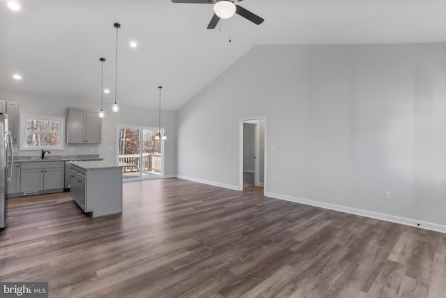 kitchen featuring baseboards, open floor plan, dark wood-type flooring, a center island, and gray cabinetry