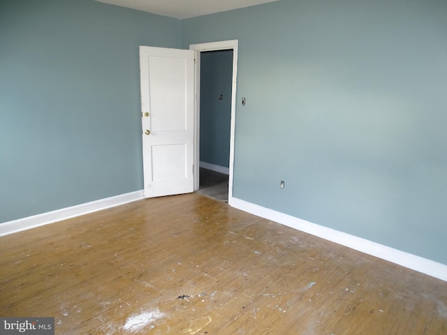 unfurnished room with hardwood / wood-style flooring and baseboards