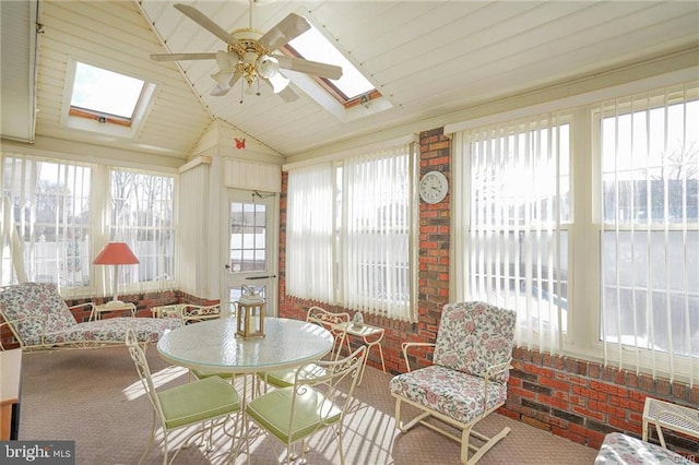 sunroom with ceiling fan, vaulted ceiling with skylight, and a wealth of natural light