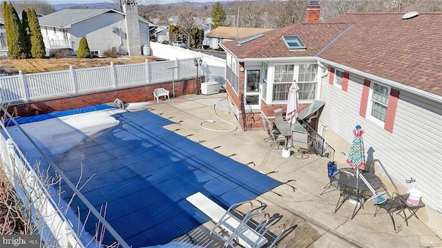 view of pool with a diving board, a patio area, a fenced backyard, and a residential view