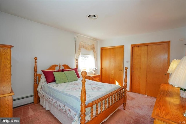 carpeted bedroom featuring visible vents, a baseboard heating unit, and multiple closets