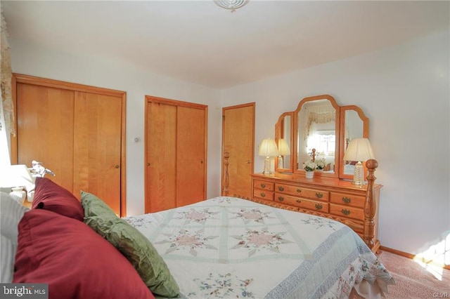 bedroom featuring carpet floors, baseboards, and two closets