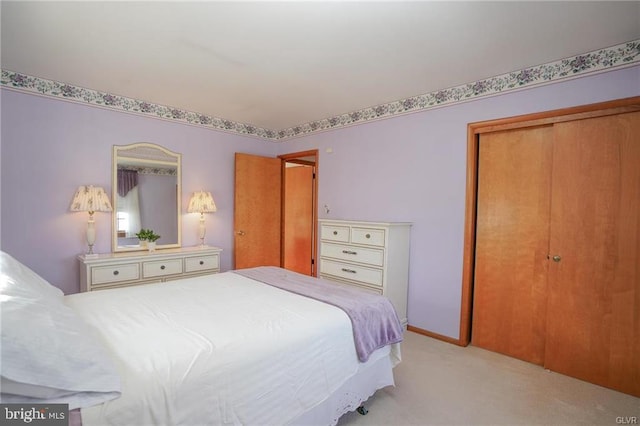 bedroom with baseboards, a closet, and light colored carpet