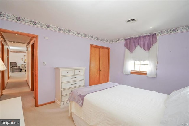 bedroom with light carpet, baseboards, visible vents, and a closet