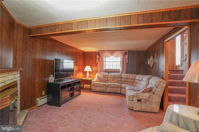 carpeted living area featuring stairway, a fireplace, a baseboard radiator, and wooden walls