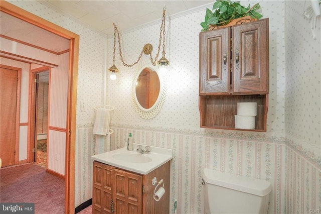 bathroom featuring ornamental molding, vanity, toilet, and wallpapered walls