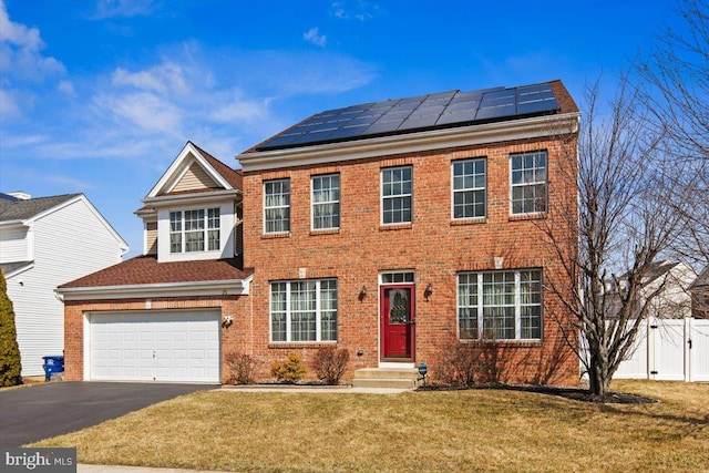 colonial inspired home featuring solar panels, aphalt driveway, fence, and a front yard