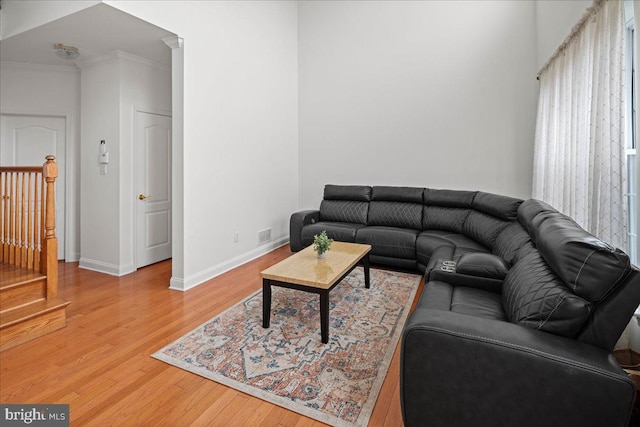 living area featuring crown molding, light wood-style flooring, and baseboards