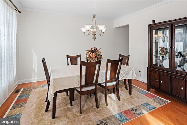 dining room with crown molding, light wood-style flooring, a notable chandelier, and visible vents