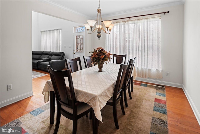 dining area with a chandelier, baseboards, wood finished floors, and crown molding