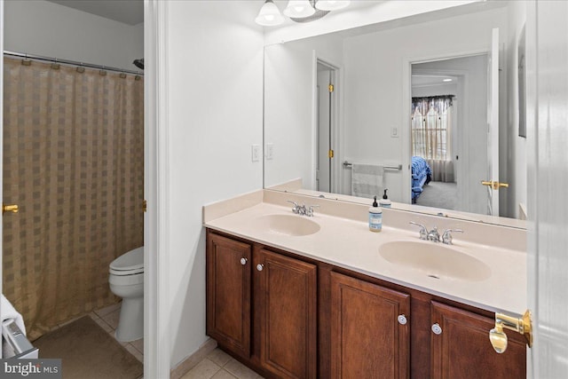 bathroom with tile patterned flooring, double vanity, toilet, and a sink