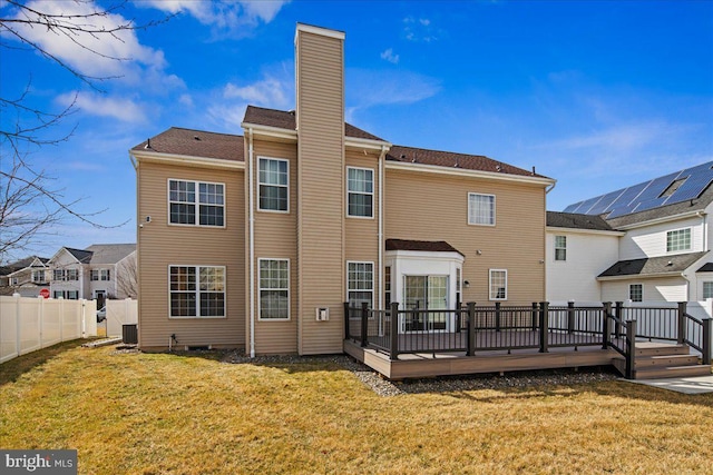 back of property featuring a lawn, a deck, a chimney, and fence