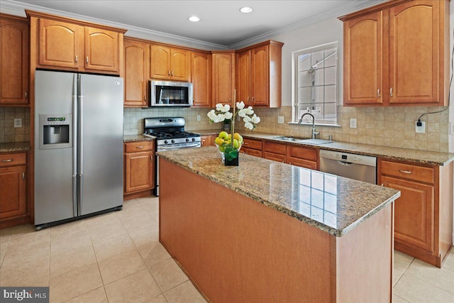 kitchen featuring a kitchen island, ornamental molding, light stone counters, appliances with stainless steel finishes, and a sink