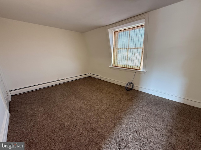 spare room with a baseboard heating unit, dark colored carpet, and baseboards