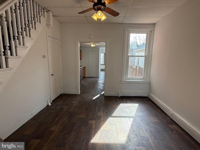 interior space with dark wood-style floors, baseboards, stairway, and a drop ceiling