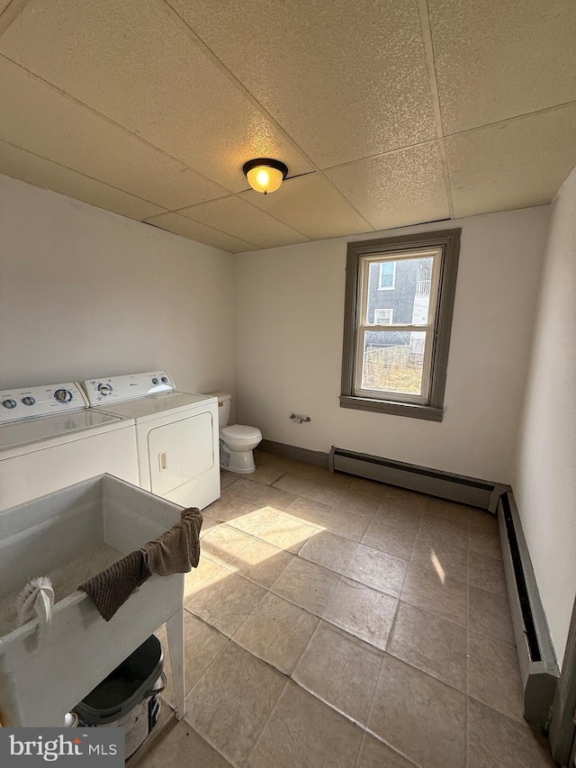 bathroom featuring washing machine and clothes dryer, a paneled ceiling, a baseboard radiator, toilet, and a baseboard heating unit