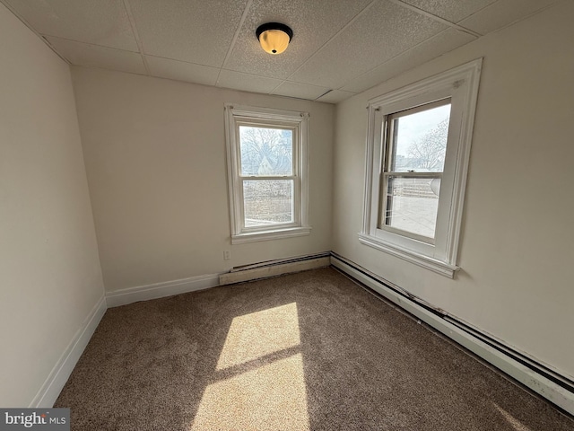 carpeted spare room featuring baseboards, baseboard heating, and a drop ceiling