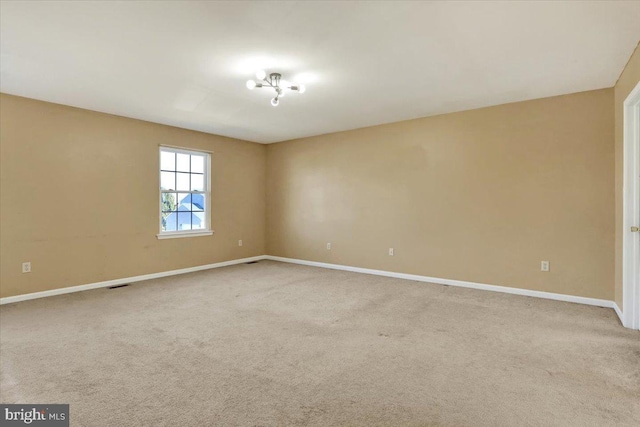 spare room with visible vents, baseboards, and light colored carpet