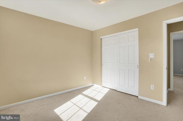 unfurnished bedroom featuring carpet, a closet, and baseboards