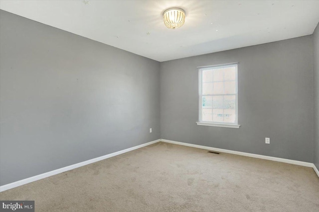 spare room with visible vents, baseboards, and carpet