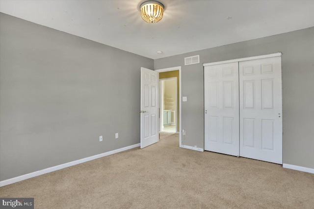 unfurnished bedroom with carpet flooring, baseboards, visible vents, and a closet