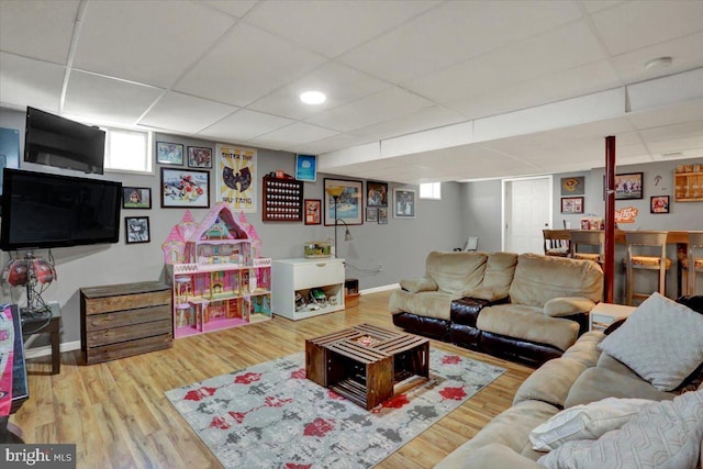 living area featuring a paneled ceiling, baseboards, and wood finished floors