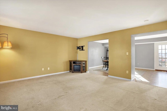 unfurnished living room with carpet and baseboards