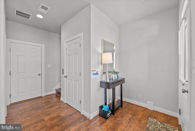 hallway with baseboards, visible vents, and wood finished floors