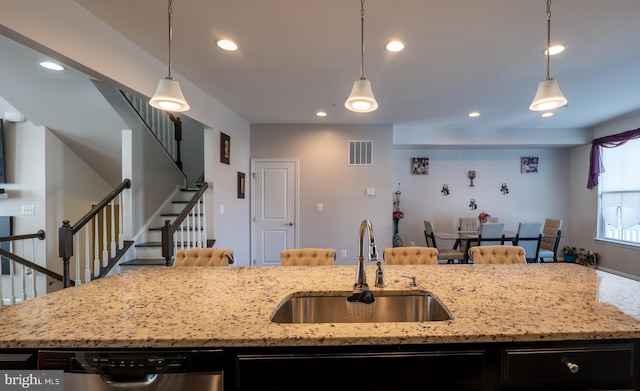 kitchen featuring decorative light fixtures, a center island with sink, visible vents, a sink, and dishwasher