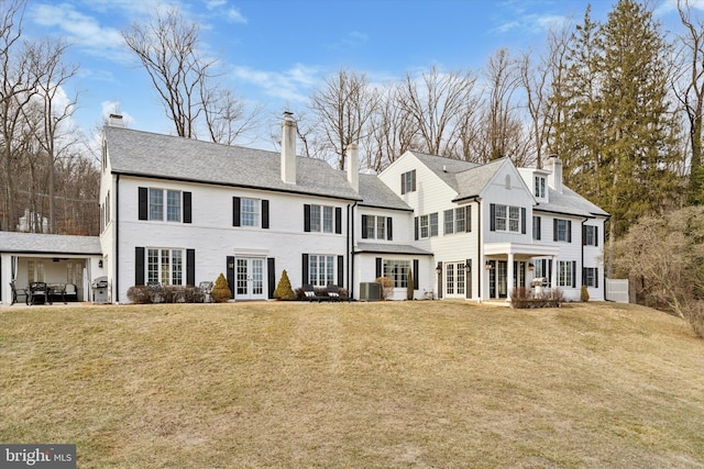 exterior space featuring french doors, a patio, a yard, a chimney, and central air condition unit