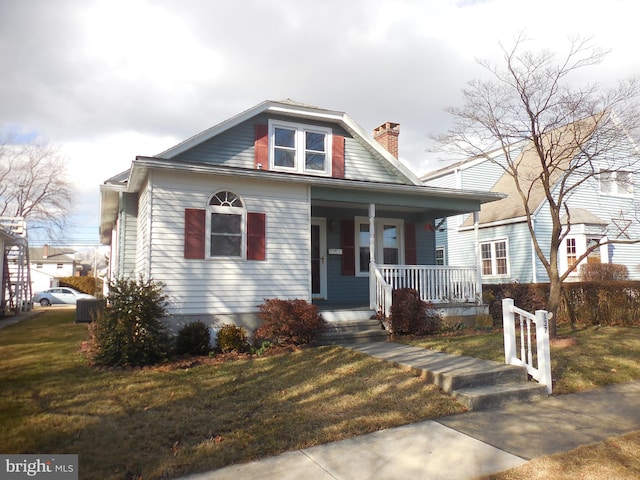 bungalow-style house with a porch, a front yard, and a chimney