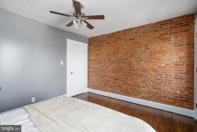 bedroom with brick wall, baseboards, ceiling fan, and wood finished floors