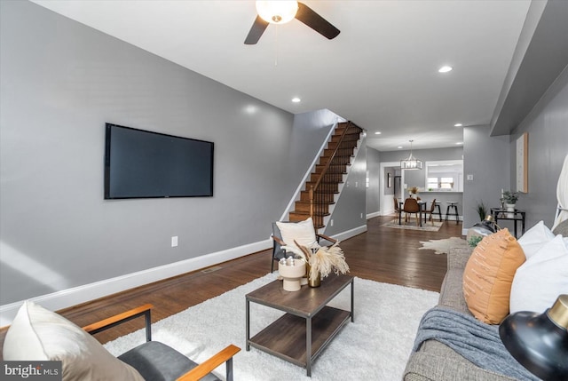 living area with recessed lighting, ceiling fan with notable chandelier, wood finished floors, baseboards, and stairs