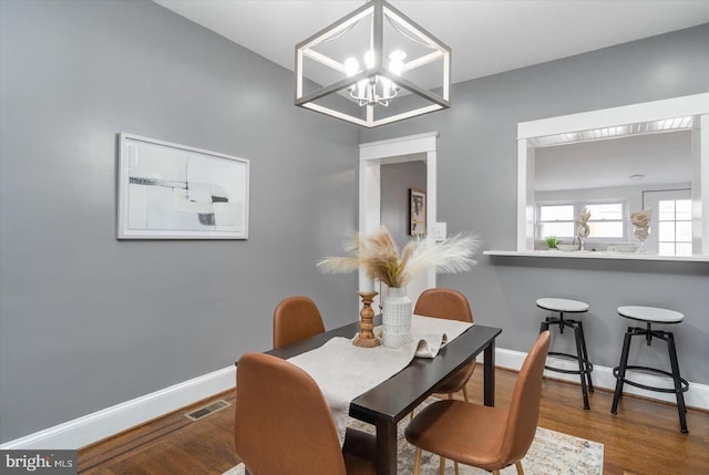 dining area with baseboards, visible vents, and wood finished floors