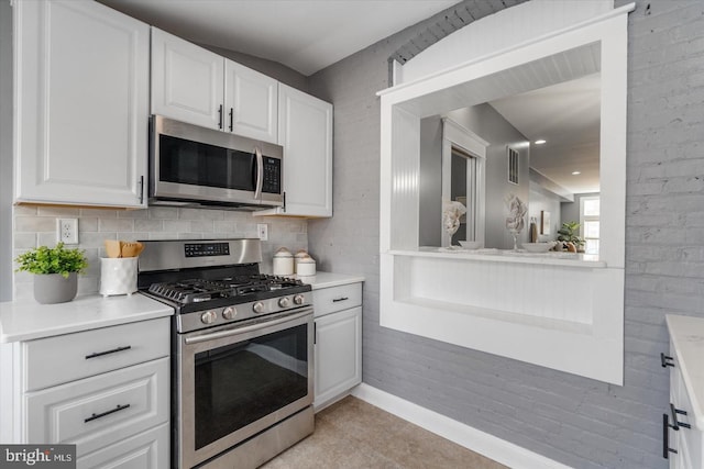 kitchen with stainless steel appliances, decorative backsplash, light countertops, and white cabinets