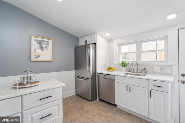 kitchen featuring light countertops, appliances with stainless steel finishes, white cabinets, wainscoting, and a sink