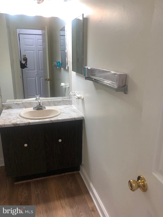 bathroom featuring vanity, baseboards, and wood finished floors