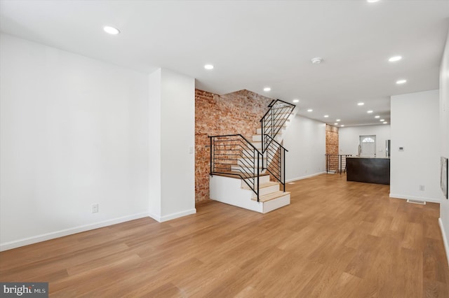 unfurnished living room featuring light wood-style flooring, stairway, baseboards, and recessed lighting