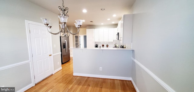 20153 Valhalla Sq, Ashburn, VA 20147 - kitchen with a peninsula, stainless steel appliances, light wood-type flooring, backsplash, and a notable chandelier