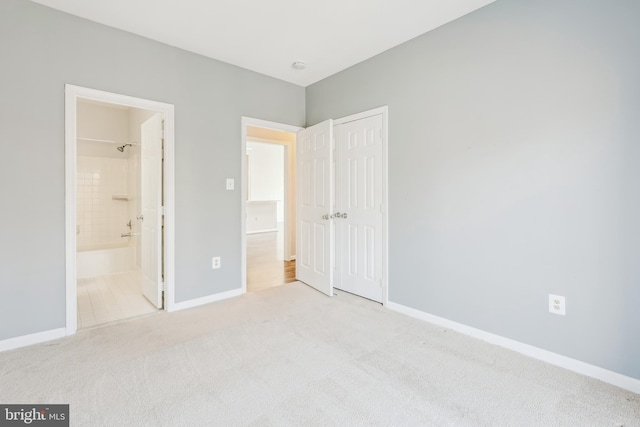 unfurnished bedroom featuring ensuite bathroom, carpet floors, a closet, and baseboards