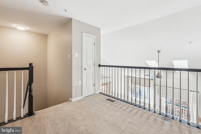 hallway with carpet floors, a skylight, baseboards, and visible vents