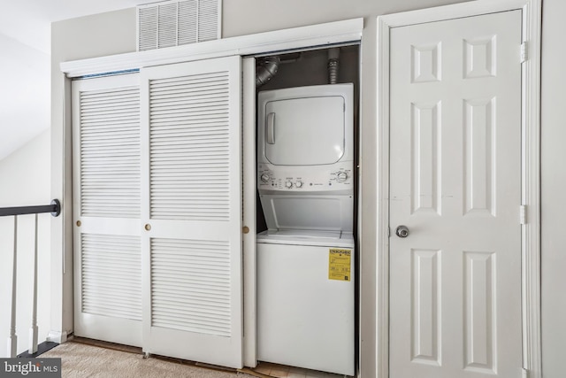 clothes washing area with stacked washing maching and dryer, visible vents, and laundry area