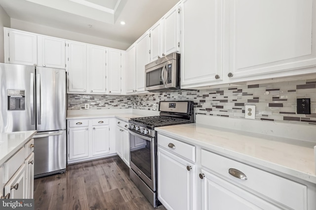 kitchen with dark wood finished floors, appliances with stainless steel finishes, white cabinetry, backsplash, and recessed lighting