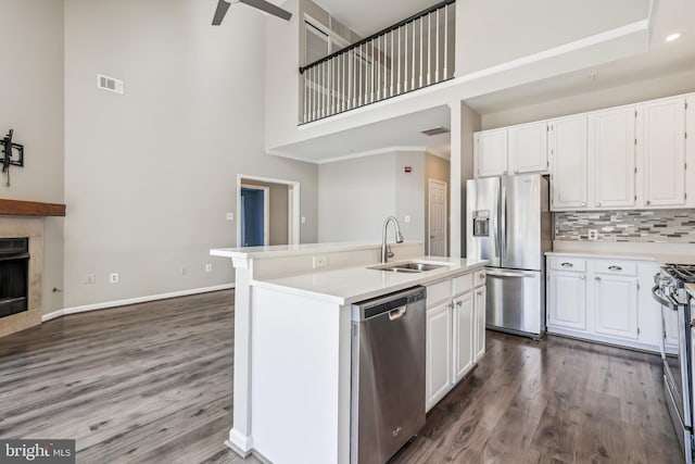 kitchen with stainless steel appliances, a fireplace, a sink, and white cabinetry