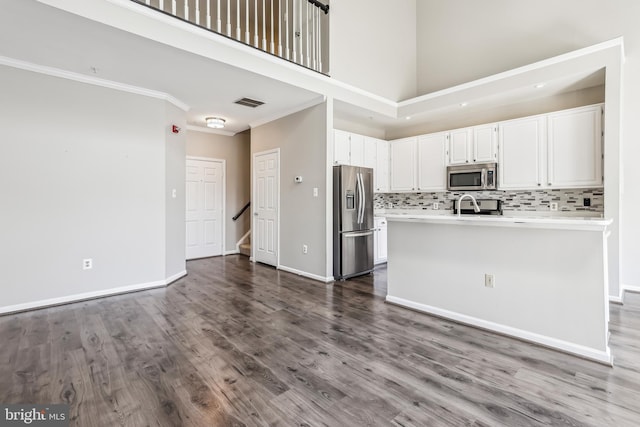 kitchen with white cabinets, dark wood-style floors, stainless steel appliances, crown molding, and backsplash