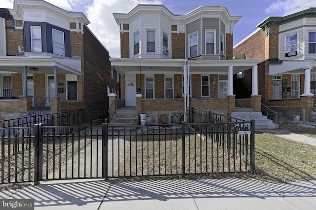 view of front of home featuring covered porch, a fenced front yard, and brick siding